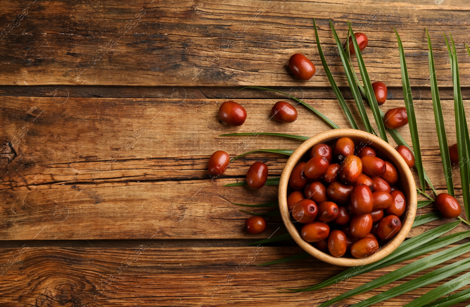 Photo of Palm oil fruits in bowl on wooden table, flat lay. Space for text