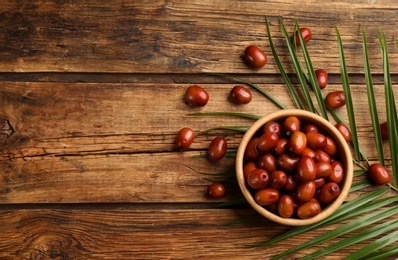 Palm oil fruits in bowl on wooden table, flat lay. Space for text