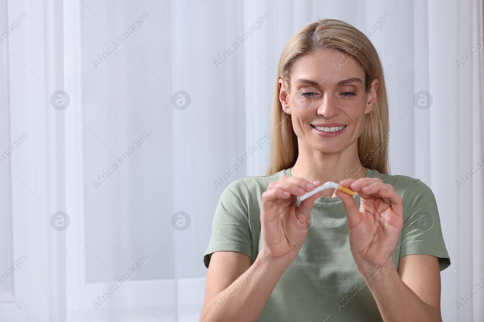 Photo of Quitting smoking concept. Happy woman breaking cigarette on light background. Space for text