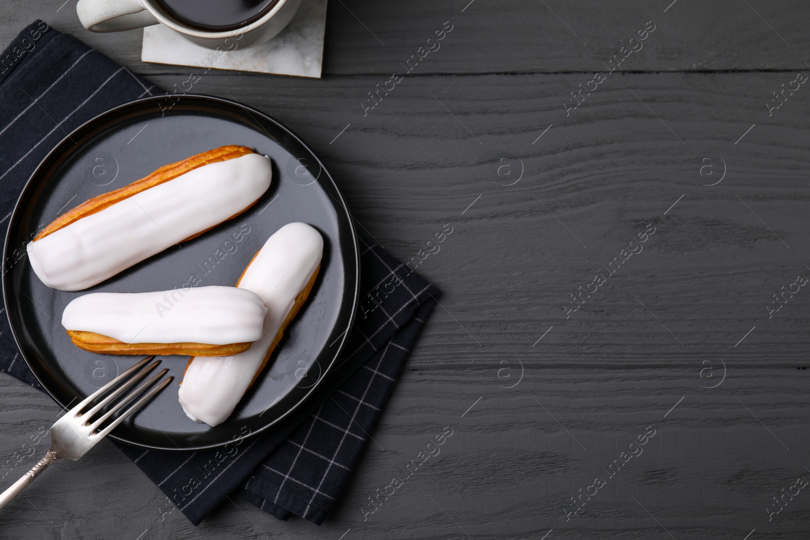 Photo of Delicious eclairs covered with glaze on grey wooden table, flat lay. Space for text