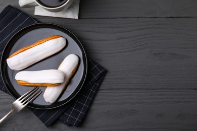 Delicious eclairs covered with glaze on grey wooden table, flat lay. Space for text