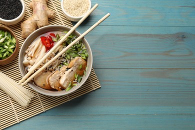 Photo of Delicious ramen with meat and ingredients on light blue wooden table, flat lay. Space for text