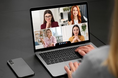 Image of Woman having video chat with coworkers via laptop at black table, closeup