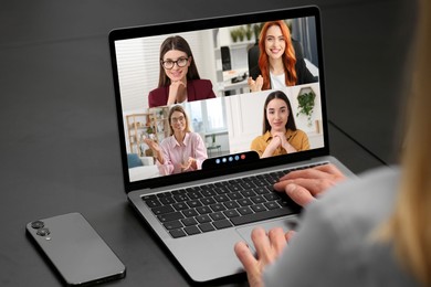 Woman having video chat with coworkers via laptop at black table, closeup