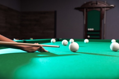 Photo of Young woman playing billiard indoors, closeup