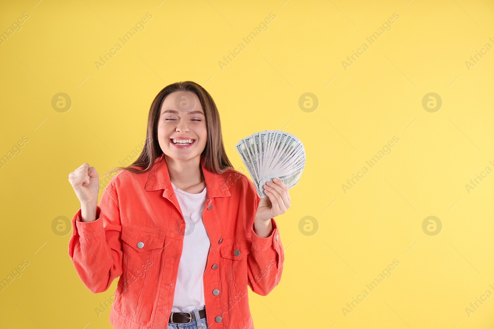 Photo of Emotional young woman with money on yellow background. Space for text