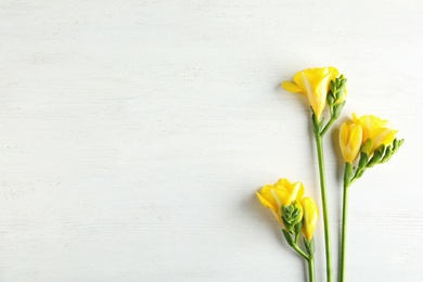 Photo of Beautiful fresh freesia flowers on wooden background, flat lay. Space for text