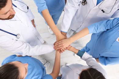 Photo of Team of medical doctors putting hands together indoors, above view
