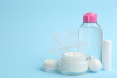Beautiful composition with cosmetic products on light blue background, space for text. Winter care.