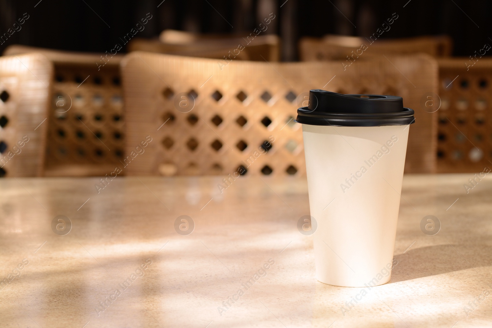 Photo of Takeaway coffee cup on beige table in cafe, space for text