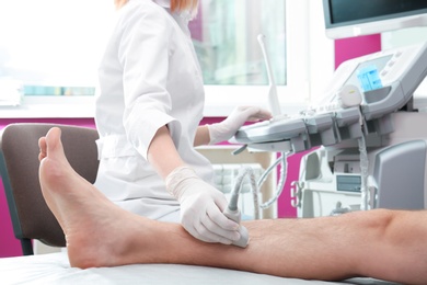 Photo of Doctor conducting ultrasound examination of patient's leg in clinic, closeup