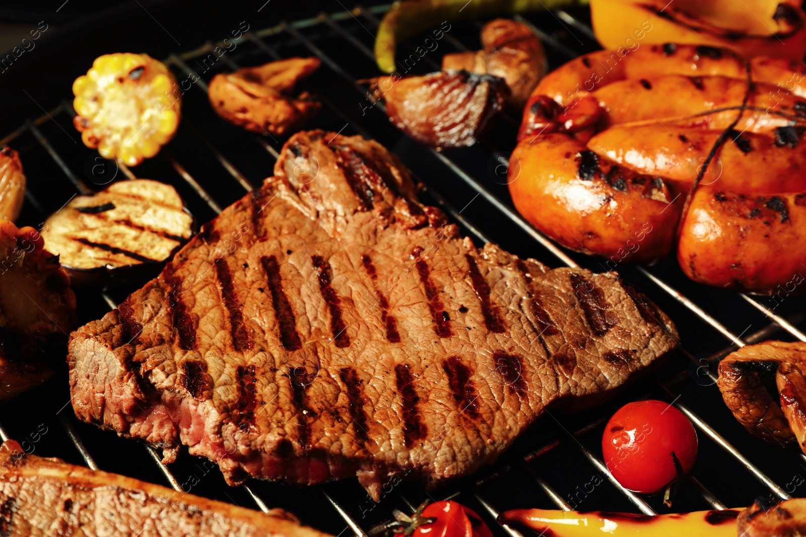 Photo of Fresh grilled meat steaks and vegetables on barbecue grate, closeup