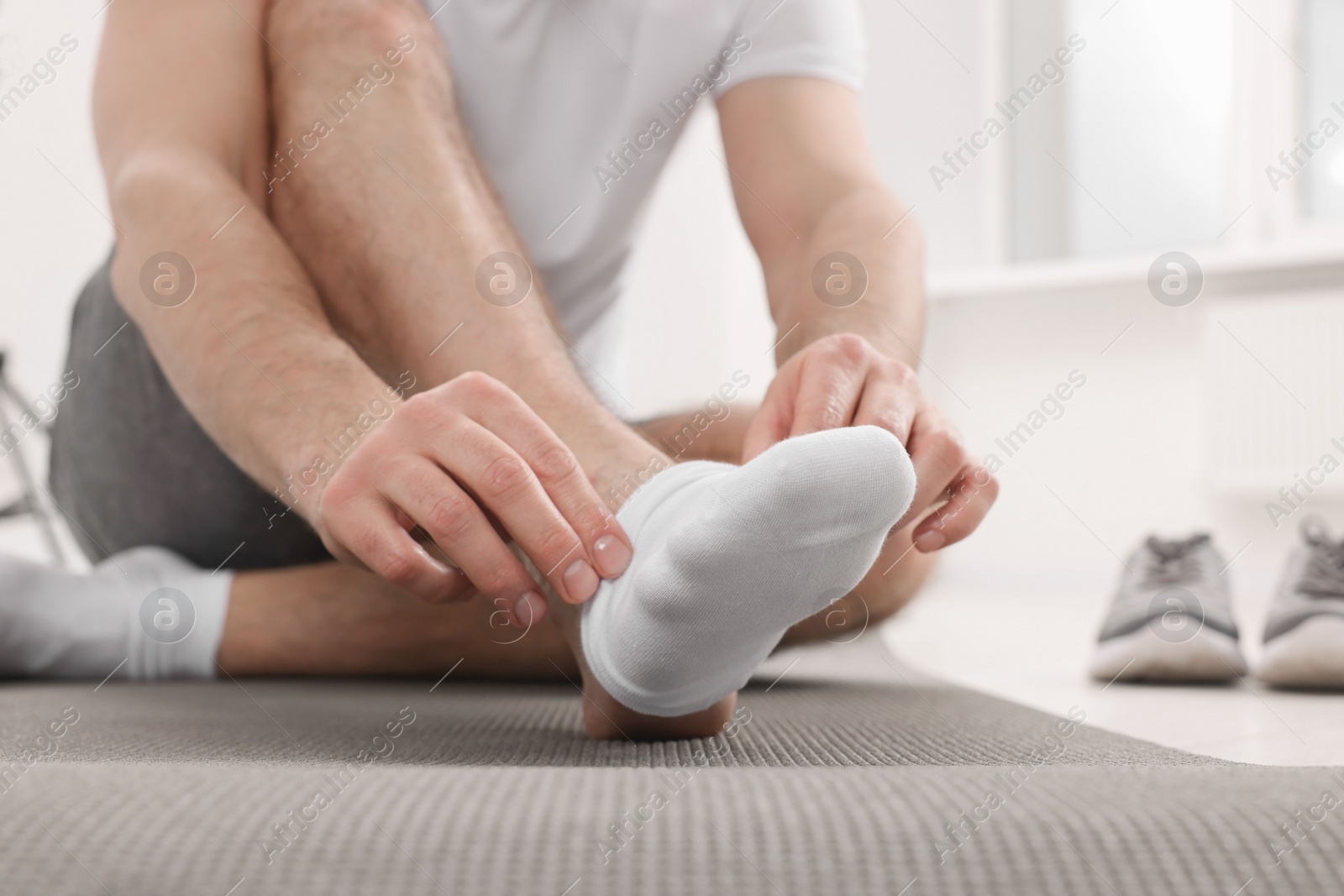 Photo of Man putting on white socks indoors, closeup