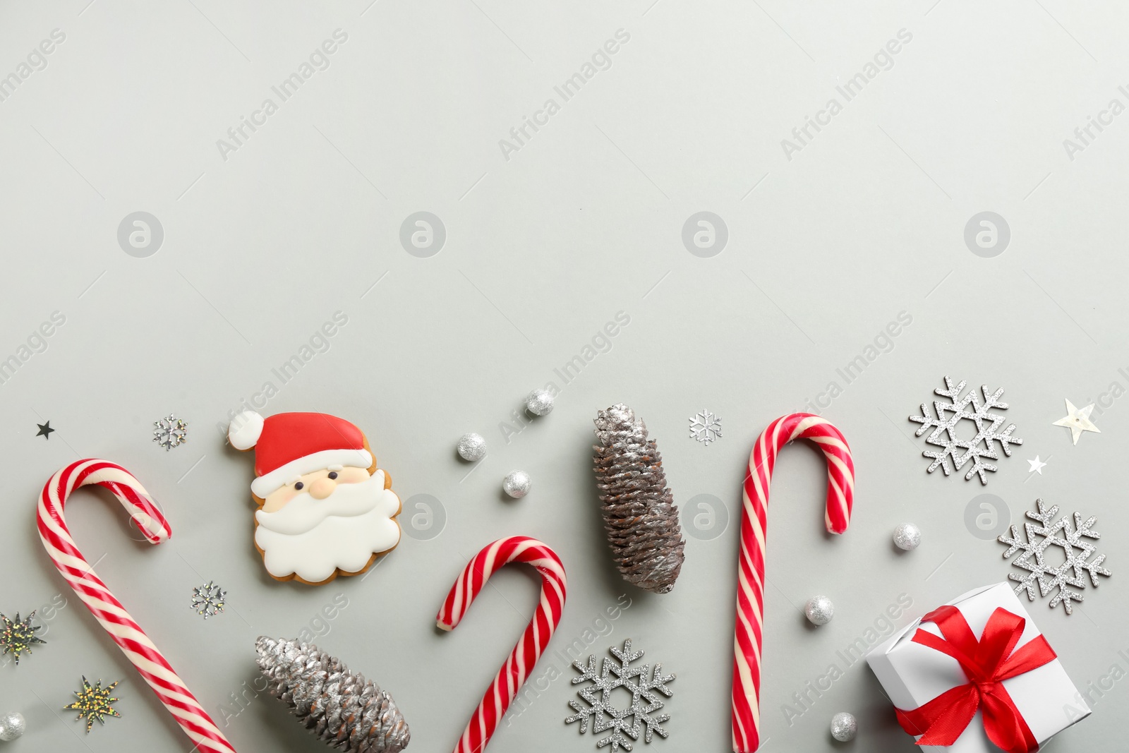 Photo of Flat lay composition with candy canes and Christmas decor on grey background. Space for text