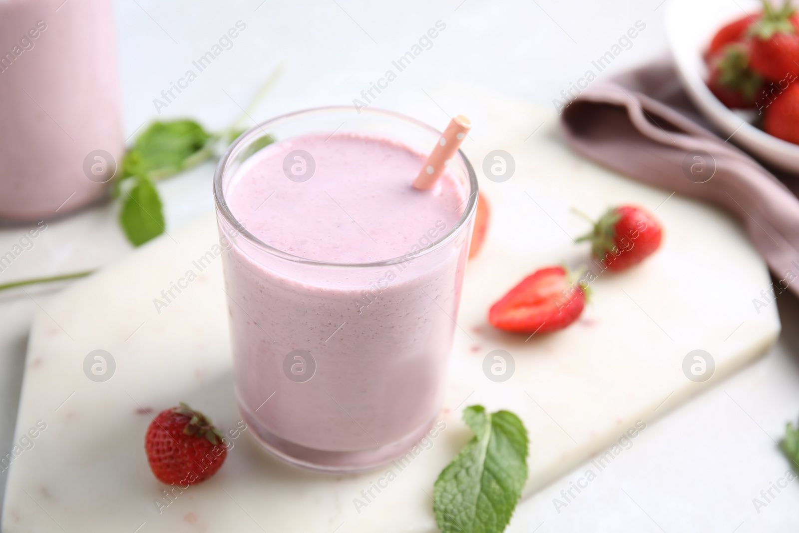 Photo of Tasty milk shake with strawberries and mint on white marble board