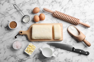 Photo of Flat lay composition of puff pastry dough and ingredients on white marble table