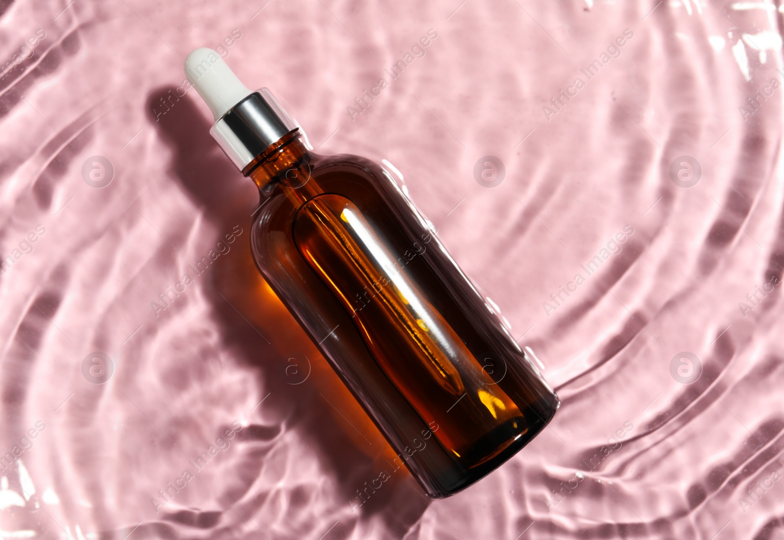 Photo of Bottle of hydrophilic oil in water on pink background, top view. Space for text