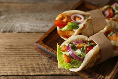 Delicious pita wrap with meat and vegetables on wooden table, closeup. Space for text