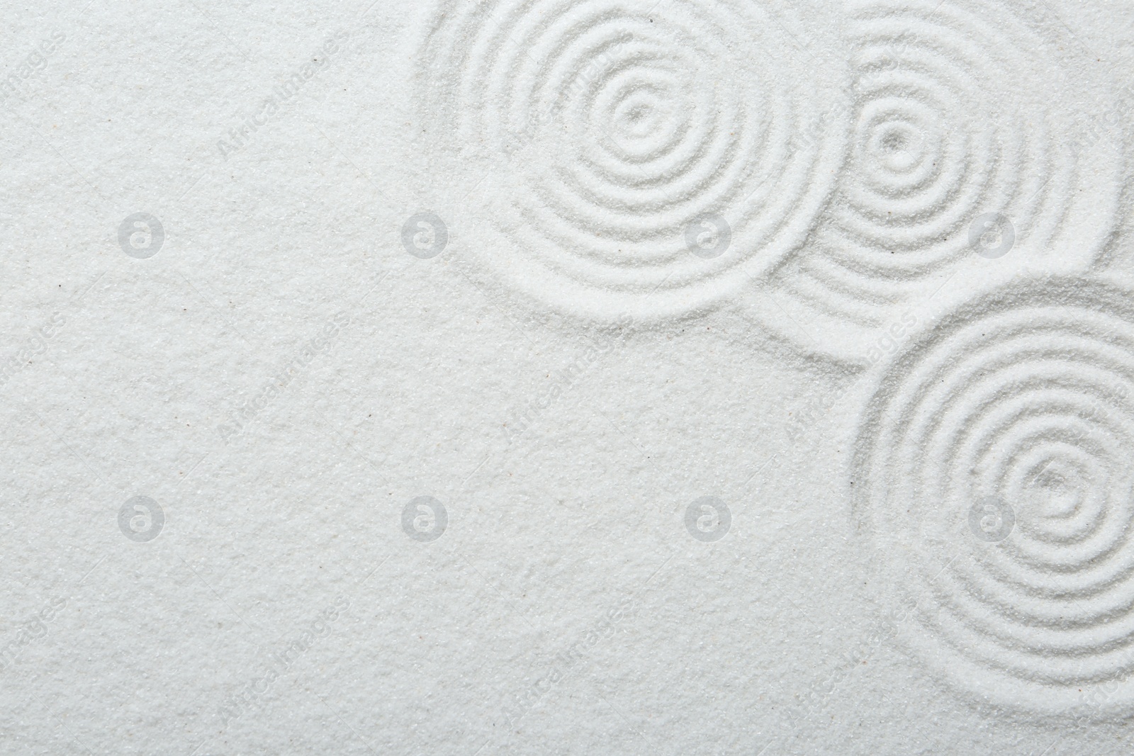 Photo of Zen rock garden. Circle patterns on white sand, top view. Space for text