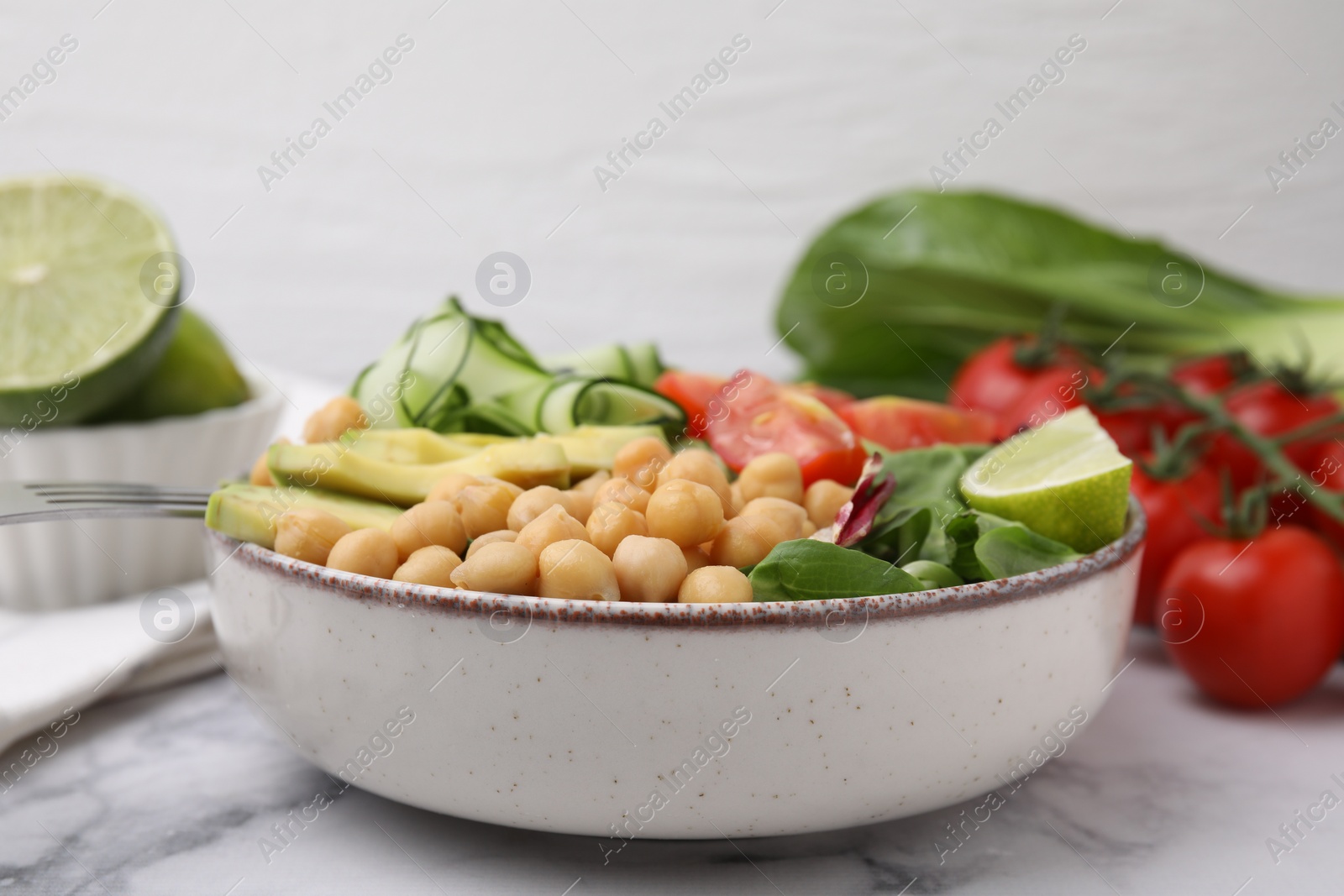 Photo of Tasty salad with chickpeas and vegetables on white marble table, closeup