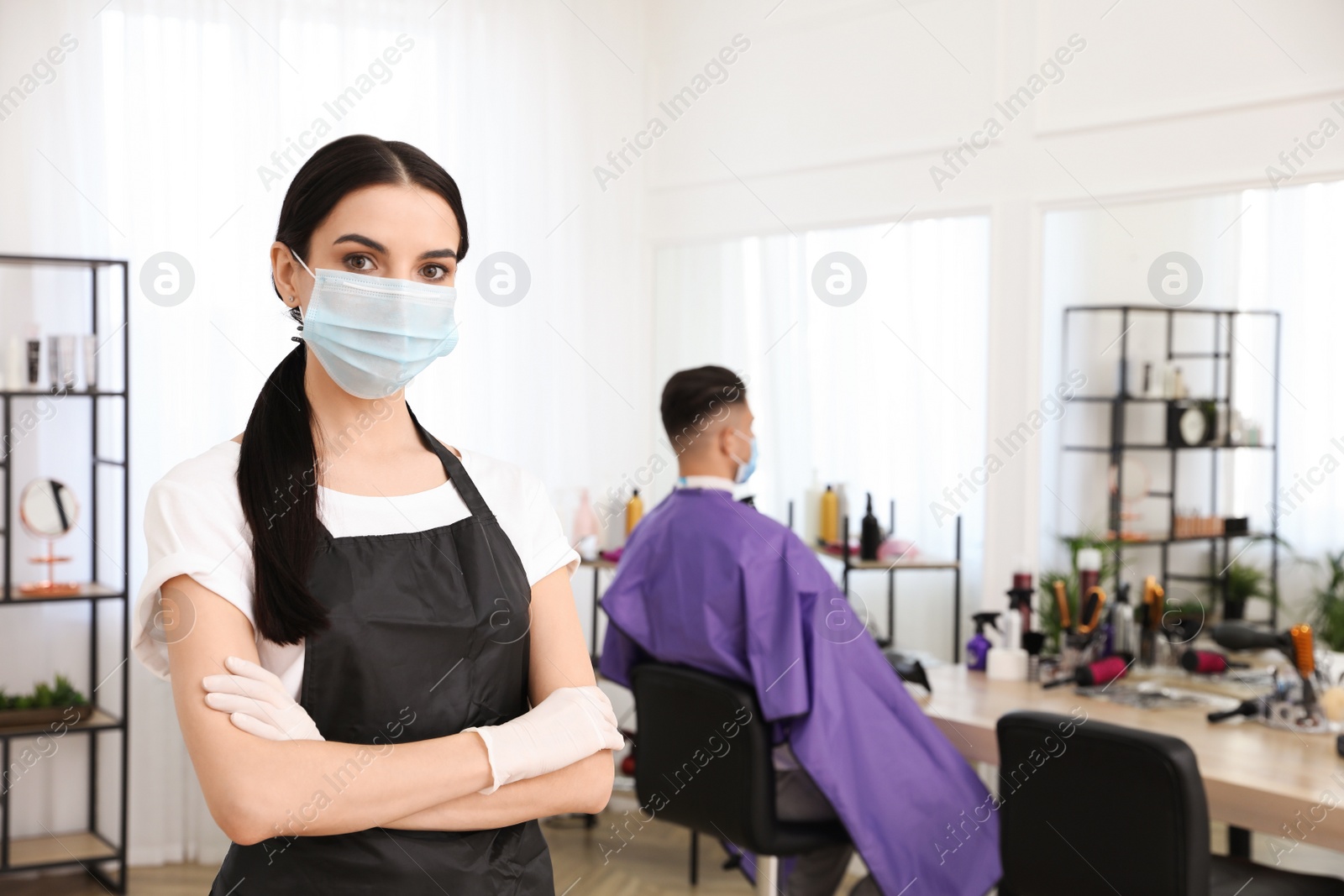 Photo of Professional stylist with protective mask in salon, space for text. Hairdressing services during Coronavirus quarantine