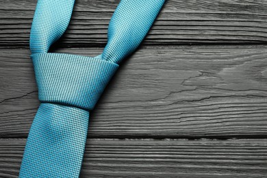 Photo of One light blue necktie on black wooden table, top view. Space for text