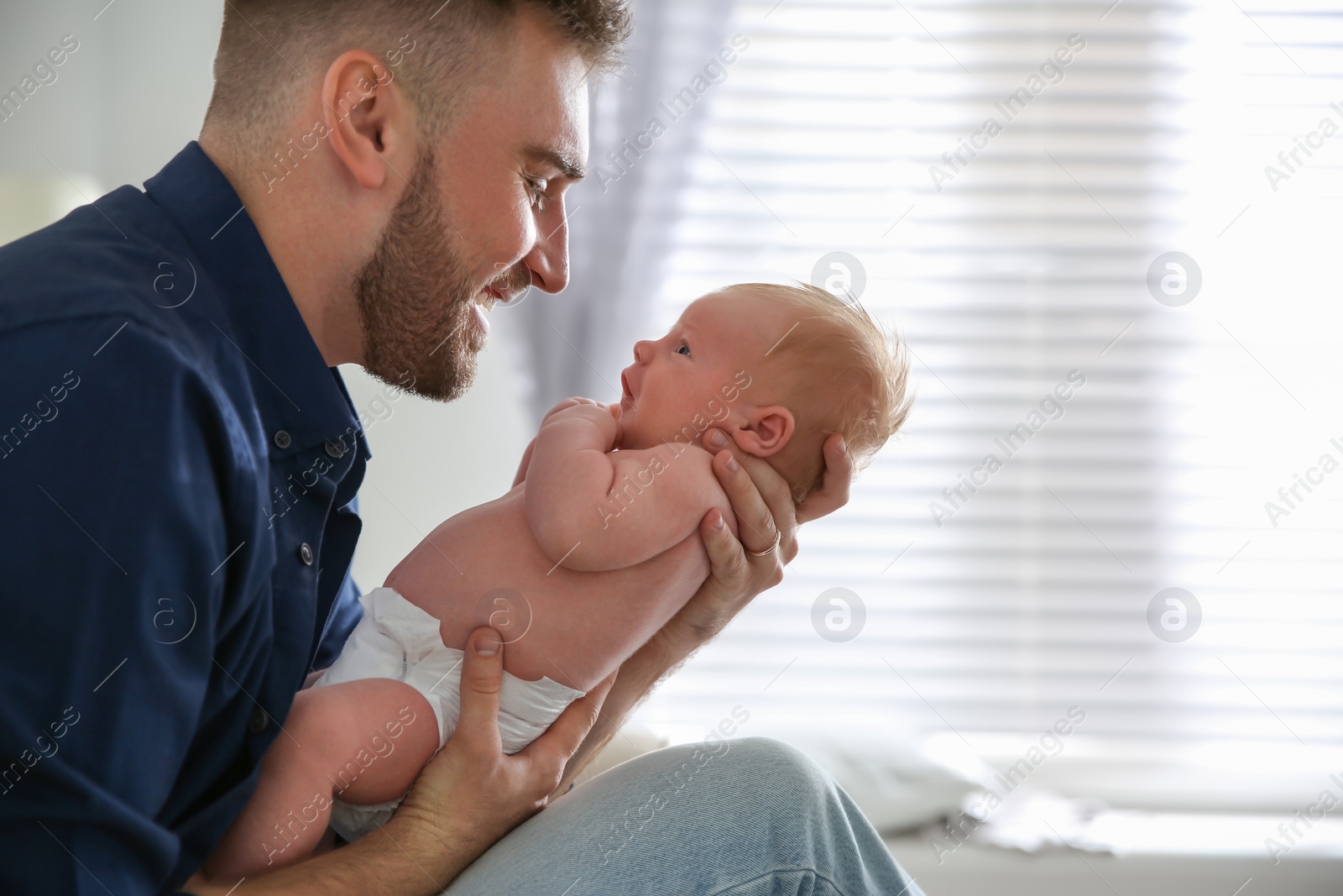 Photo of Father with his newborn son at home