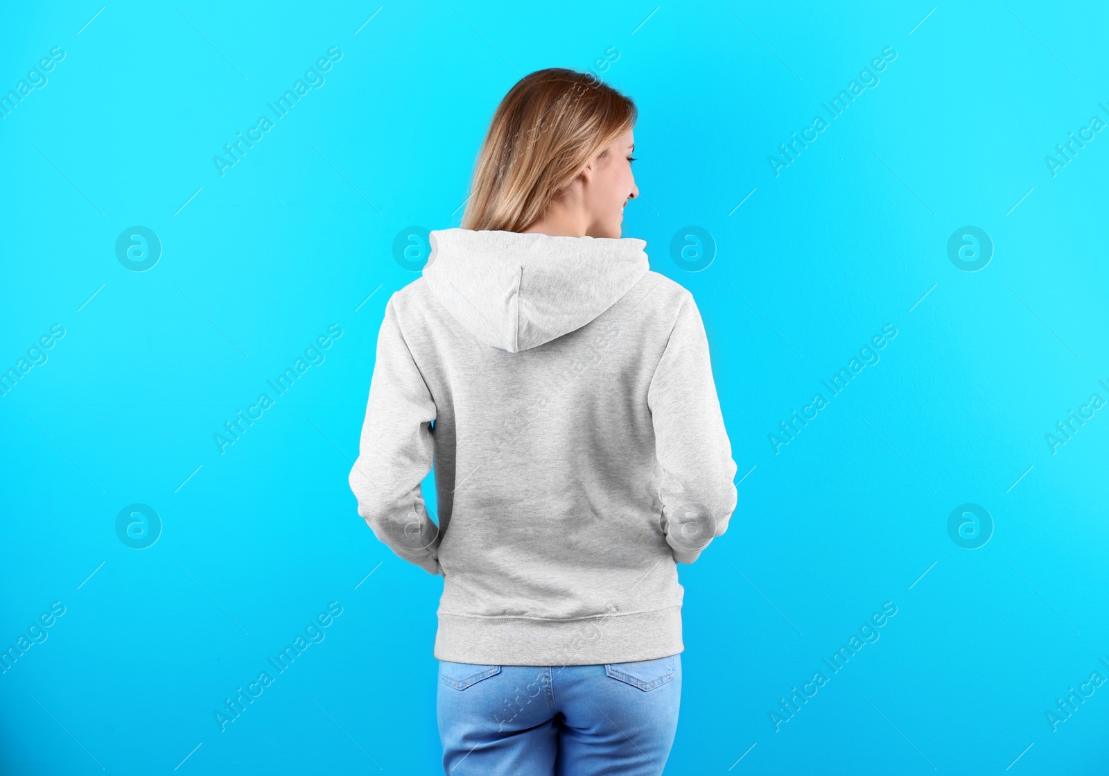 Photo of Woman in hoodie sweater on color background. Space for design