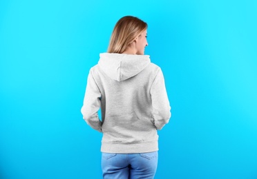 Woman in hoodie sweater on color background. Space for design