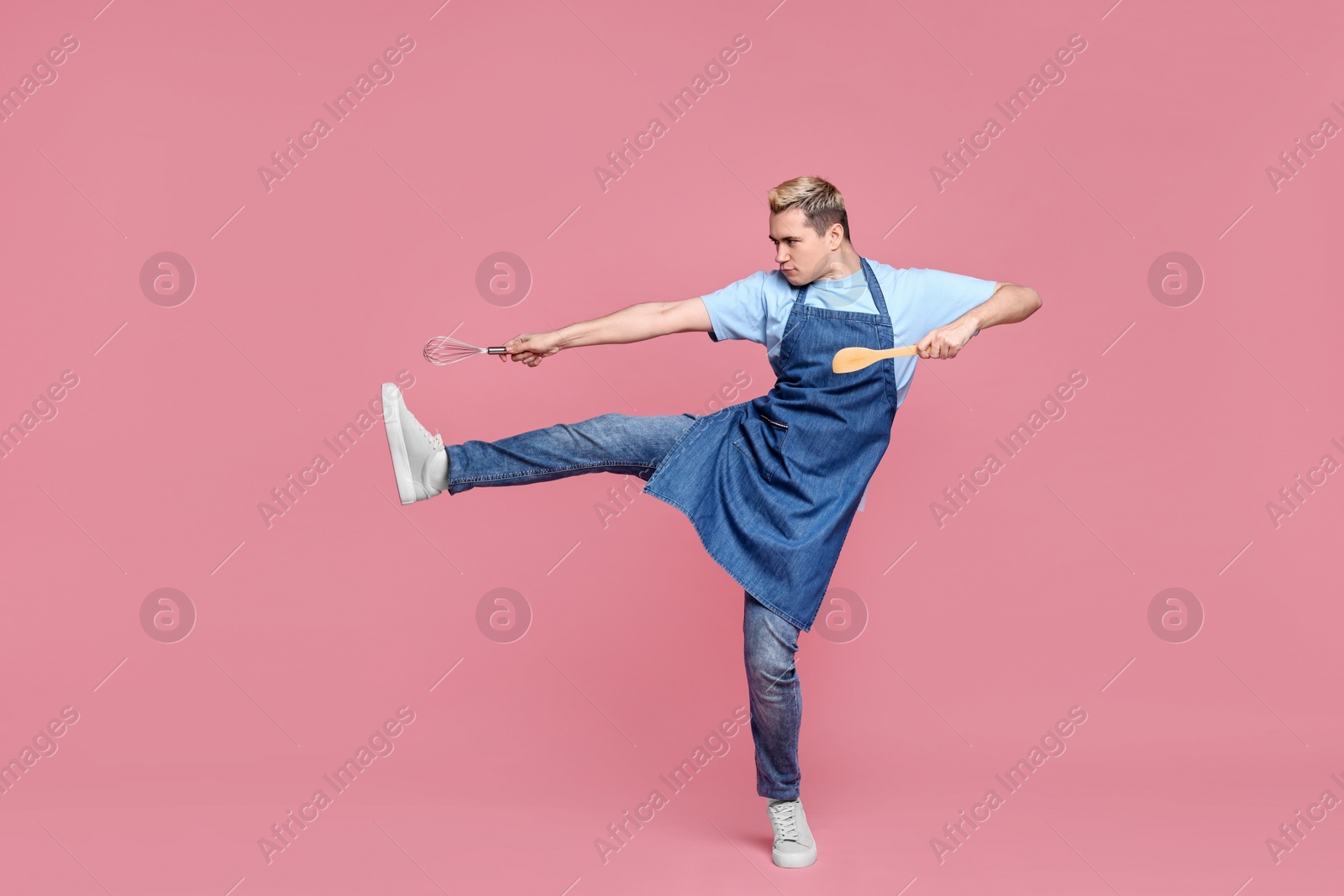 Photo of Portrait of confectioner holding spatula and whisk on pink background