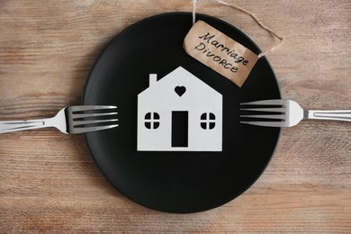 Photo of Divorce concept. Plate with model of house, paper card and forks on wooden table, flat lay