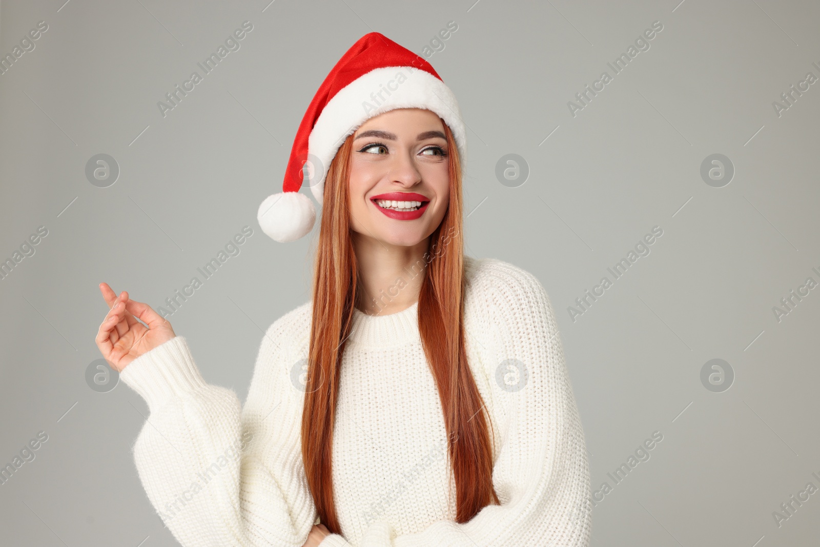 Photo of Young woman in Santa hat on light grey background. Christmas celebration