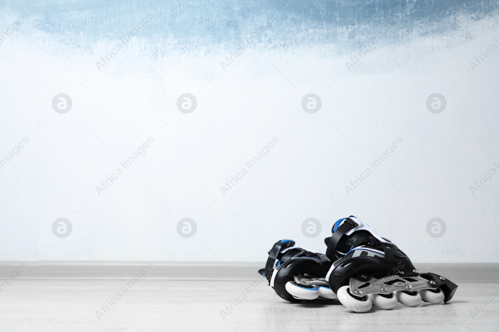 Photo of Inline roller skates on floor near color wall. Space for text