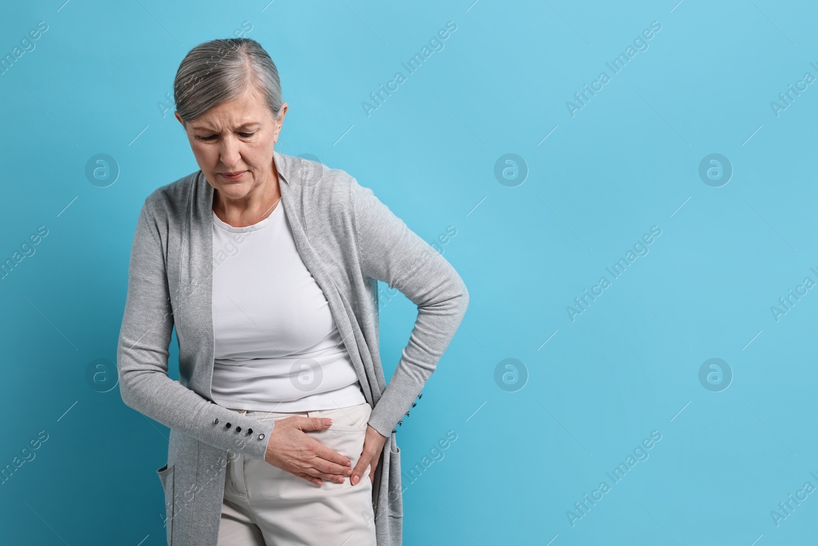 Photo of Arthritis symptoms. Woman suffering from hip joint pain on light blue background, space for text