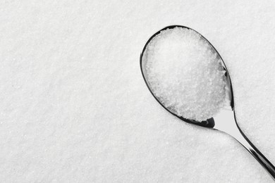 Photo of Metal spoon on granulated sugar, top view