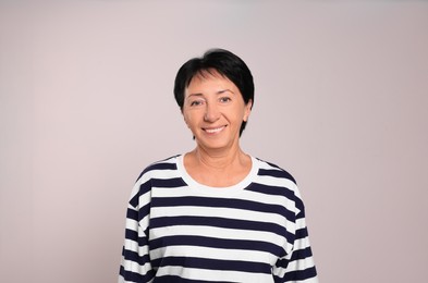 Portrait of smiling senior woman on light grey background