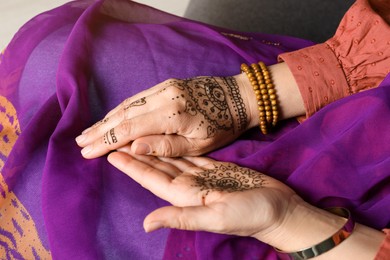 Photo of Woman with beautiful henna tattoos on hands, closeup. Traditional mehndi
