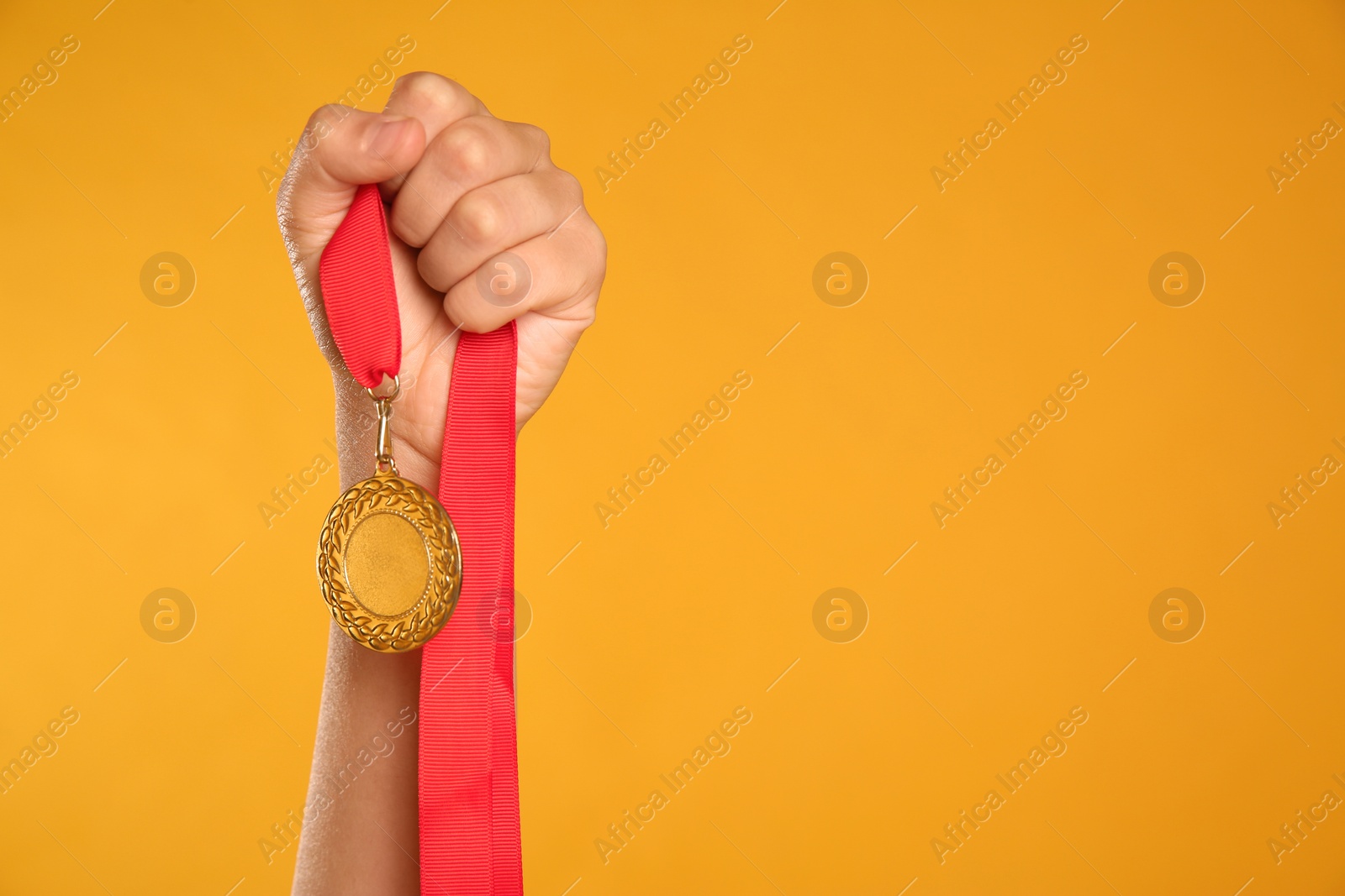 Photo of Woman holding gold medal on yellow background, closeup. Space for text