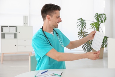 Young male doctor with cardiogram at workplace. Cardiology center