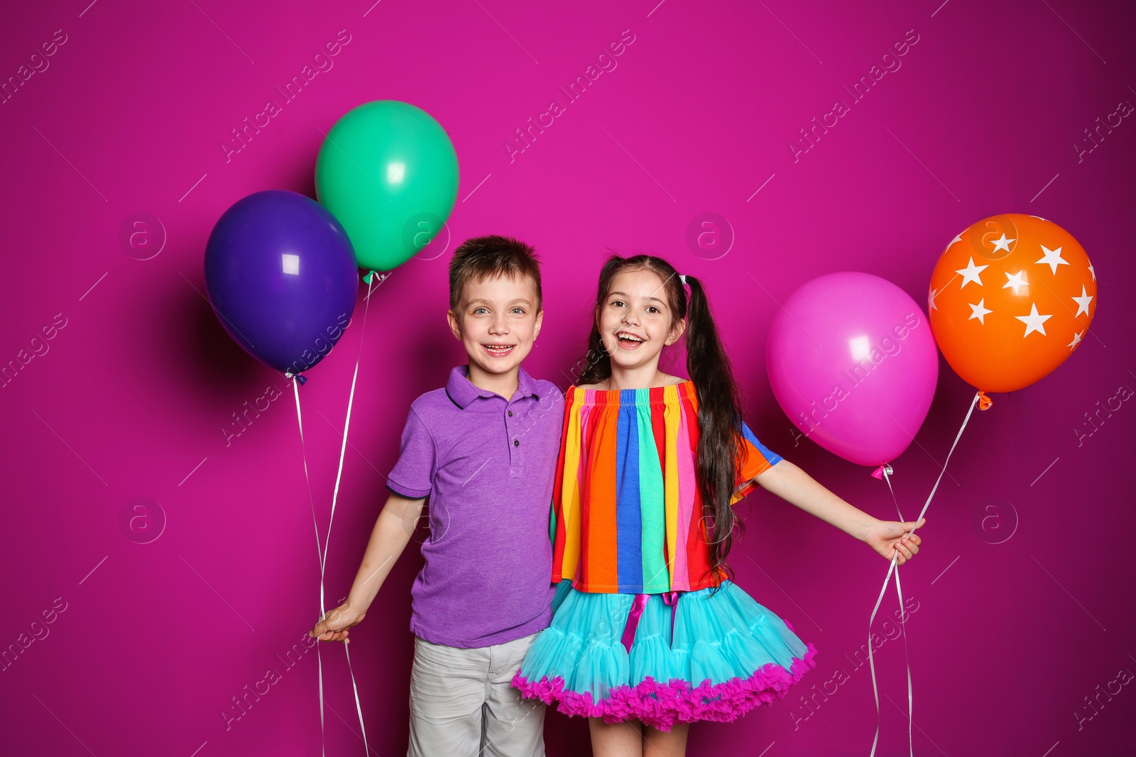 Photo of Cute girl and boy with balloons on color background. Birthday celebration