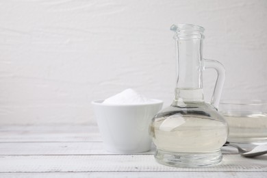 Photo of Vinegar and baking soda on white wooden table, space for text