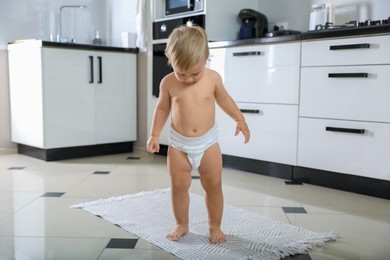 Photo of Cute baby learning to walk in kitchen