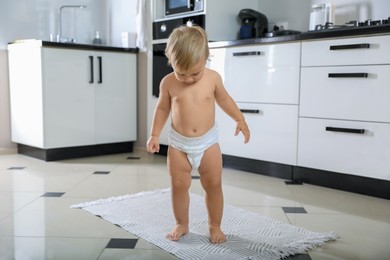 Cute baby learning to walk in kitchen