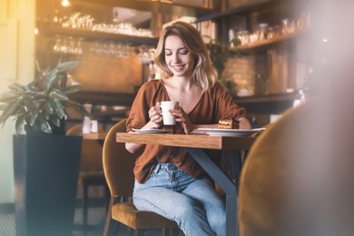 Photo of Young woman with cup of coffee at cafe in morning