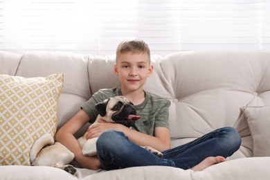 Photo of Boy with his cute pug on sofa at home