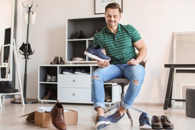 Photo of Young man trying on shoes in store