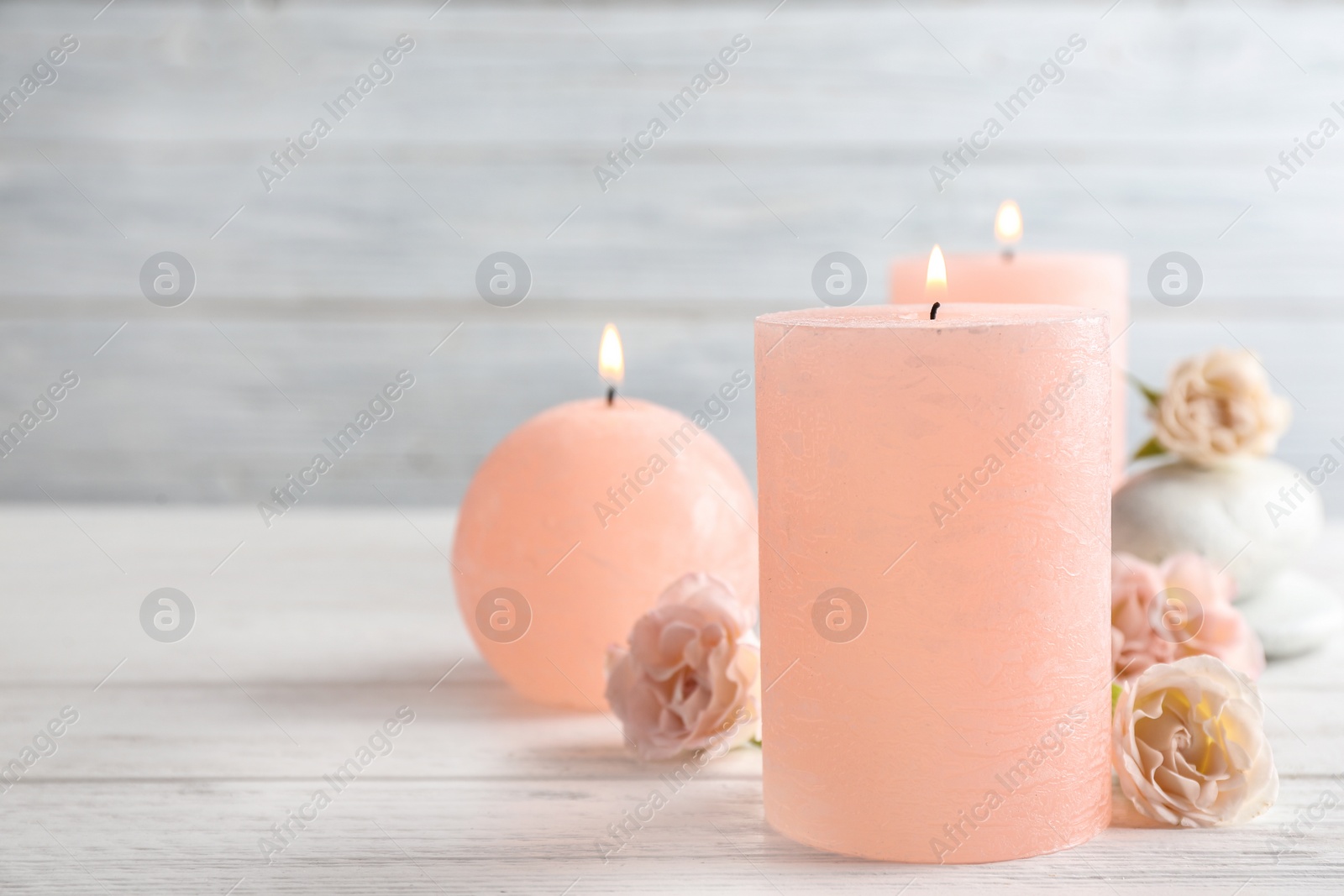 Photo of Burning candles, spa stones and flowers on table. Space for text