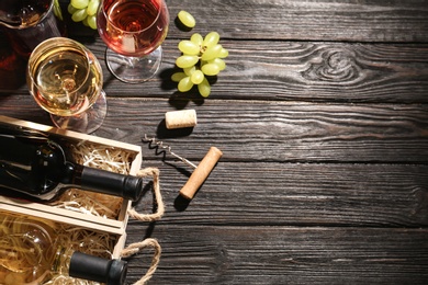 Photo of Flat lay composition with crates and bottles of wine on wooden table. Space for text