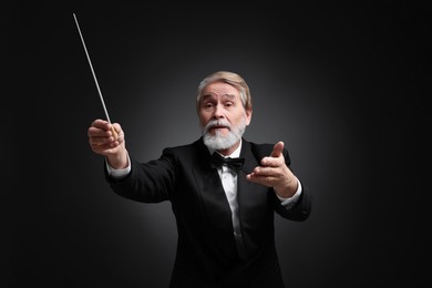 Professional conductor with baton on black background