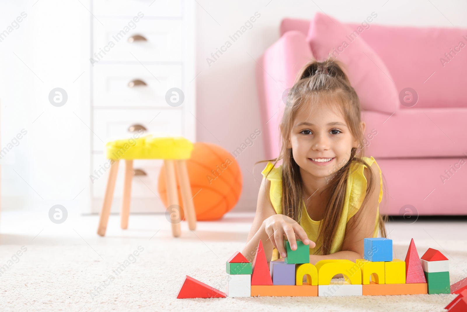 Photo of Cute little child playing with building blocks on floor, indoors